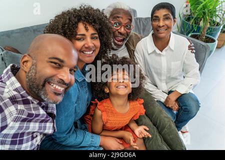 Happy family sitting on sofa while taking selfie Foto Stock