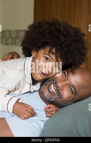 Smiling father and daughter relaxing on bed Foto Stock