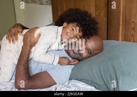 Sorridente padre e figlia che si rilassano a letto Foto Stock