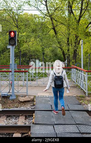 Mosca, Russia - 21 maggio 2022: Donna che corre attraverso le rotaie su rosso. Movimento di sfocatura Foto Stock