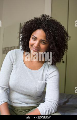 Donna sorridente seduta sul letto Foto Stock