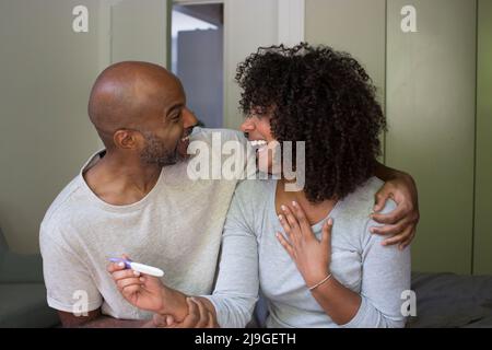 Coppia sorridente che tiene il kit di test di gravidanza Foto Stock