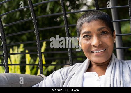 Donna matura sorridente seduta su una sedia a dondolo Foto Stock