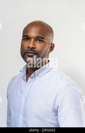 Close-up of smiling man standing against white wall Foto Stock