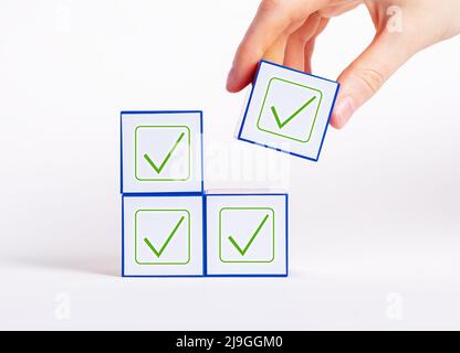 Decisioni affermative all'unanimità. Cubo di tenuta manuale con segno di spunta. Voto, unità nei pensieri, conformismo, concetto di approvazione. Foto di alta qualità Foto Stock