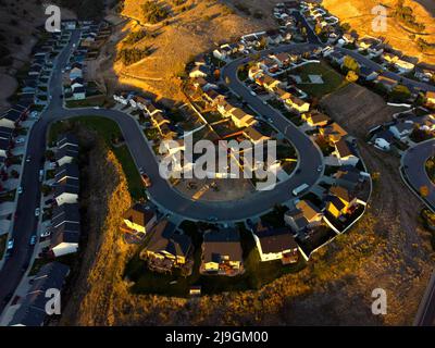 Vista aerea da un drone di un quartiere suburbano con case cantieri e automobili luce tarda sera Foto Stock