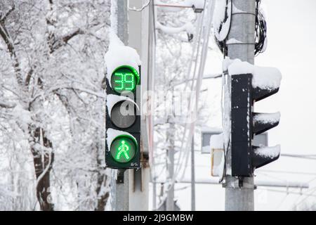 Un semaforo verde in inverno in neve e ghiaccio in Ucraina nella città di Dnipro, le strade sono state sollevate, un semaforo in città Foto Stock