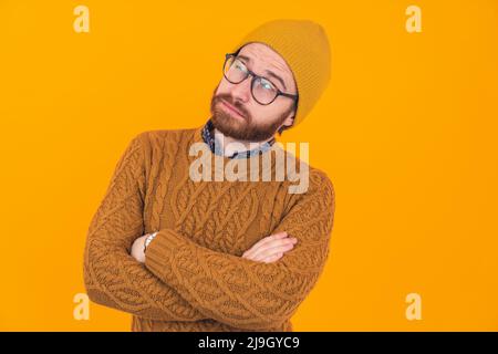 È tempo di pensare. Caucasico baccato in maglione lavorato a maglia con braccia incrociate e faccia sognante su sfondo giallo. Foto di alta qualità Foto Stock