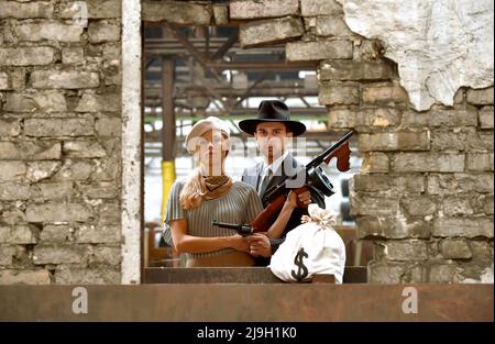 Una giovane coppia si veste in 1930 capi di abbigliamento stile. Ognuno di loro porta un'arma come agiscono il ruolo del famoso duo gangster Bonnie e Clyde. Foto Stock