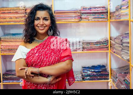 donna d'affari in rosso sari tradizionale e gioielleria abbigliamento proprietario cashmere yak lana shawls.female venditore in goa india arambol vendita shop.designer Foto Stock