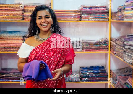 donna d'affari in rosso sari tradizionale e gioielleria abbigliamento proprietario cashmere yak lana shawls.female venditore in goa india arambol vendita shop.designer Foto Stock