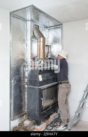 Installazione di lana minerale con lamina intorno al camino per la protezione termica e le alte temperature per le pareti, lavori di installazione. Foto Stock