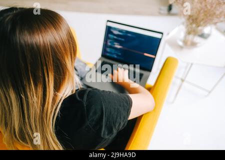 Giovane donna sviluppatore mobile scrive il codice del programma su un computer, lavoro del programmatore. Foto Stock
