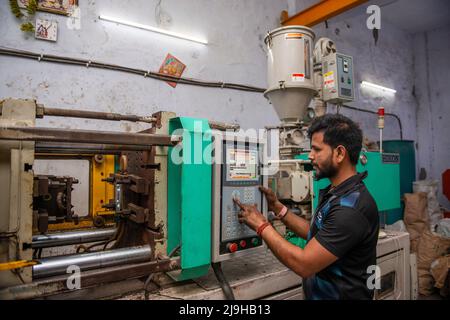 New Delhi, India. 23rd maggio 2022. Un lavoratore gestisce una macchina di stampaggio automatica presso una fabbrica di produzione di prodotti plastici a Nuova Delhi. (Foto di Pradeep Gaur/SOPA Images/Sipa USA) Credit: Sipa USA/Alamy Live News Foto Stock