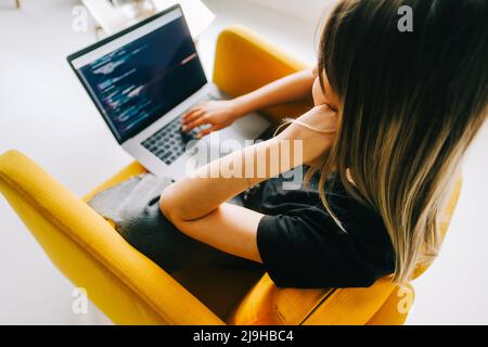 Giovane donna sviluppatore mobile scrive il codice del programma su un computer, lavoro del programmatore. Foto Stock
