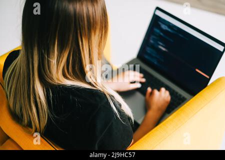 Giovane donna sviluppatore mobile scrive il codice del programma su un computer, lavoro del programmatore. Foto Stock