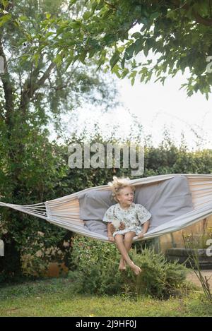 Ragazza giocosa che oscilla in amaca in giardino Foto Stock