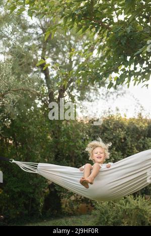 Ragazza che oscilla in amaca in giardino Foto Stock