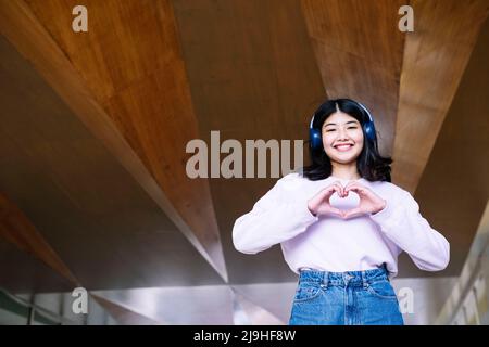 Donna felice che fa segno di forma del cuore con le mani Foto Stock