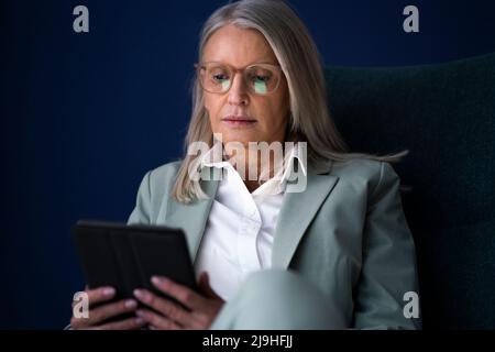 Donna d'affari che utilizza un tablet PC su sfondo blu Foto Stock