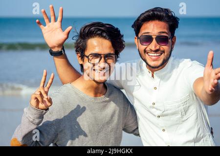 Holi felice due indian elegante mans giovani amici abbracciato sulla spiaggia dal mare.a lungo atteso incontro diwali dei fratelli in India Goa tropicale Foto Stock