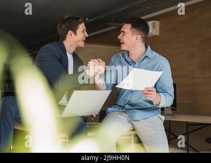 Due colleghi felici che scuotono le mani in ufficio Foto Stock