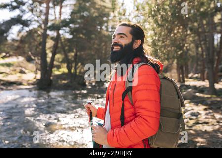 Felice uomo portatore che indossa zaino in piedi nella foresta Foto Stock