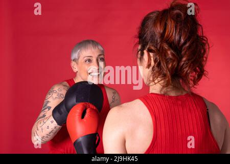 Donna felice boxe con un amico su sfondo rosso Foto Stock