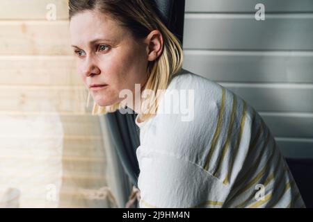 Donna triste che guarda fuori dalla finestra a casa Foto Stock