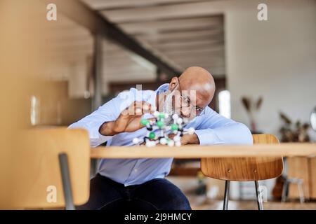 Scienziato che esamina la struttura molecolare sulla scrivania a casa Foto Stock