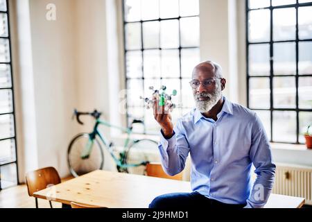 Struttura molecolare dello scienziato maturo seduta sulla scrivania a casa Foto Stock