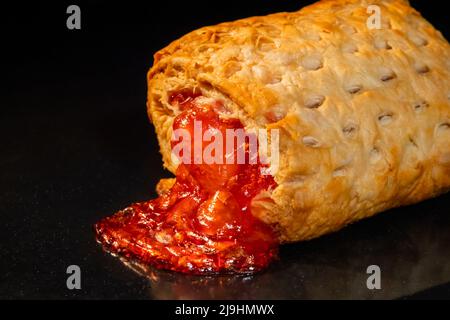 Una panna al forno con marmellata di fragole rosse su vassoio nel forno elettrico, fondo nero Foto Stock