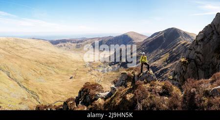Donna in piedi in cima alla scogliera rocciosa in giornata di sole Foto Stock