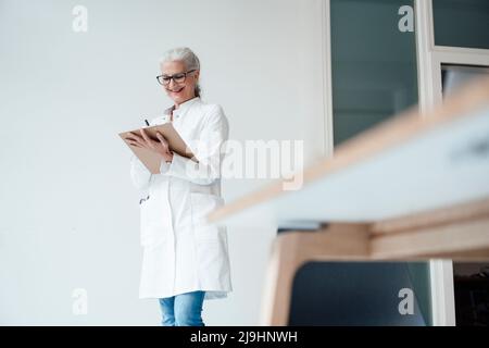 Buon medico in piedi e scrivere sugli appunti Foto Stock