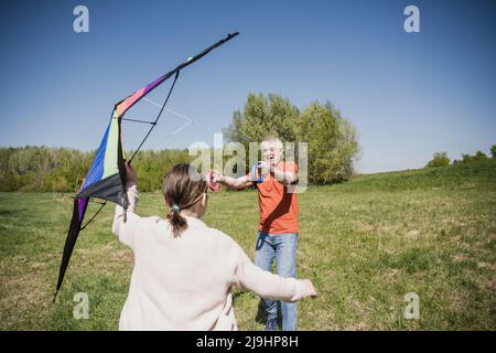 Nipote aiutare nonno a volare aquilone in giorno di sole Foto Stock