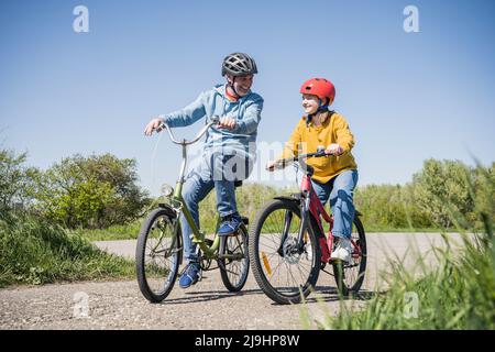 Buon nonno con nipote in bicicletta sul sentiero Foto Stock