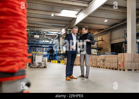 Strategia di pianificazione aziendale con i colleghi rispetto ai tablet PC in warehouse Foto Stock