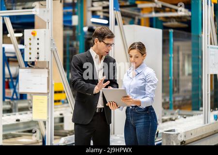 Uomo d'affari che parla con un collega di tablet PC in magazzino Foto Stock