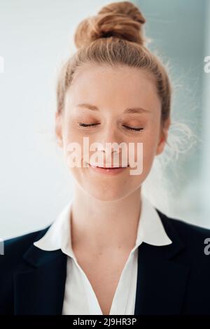 Donna d'affari sorridente con gli occhi chiusi in ufficio Foto Stock