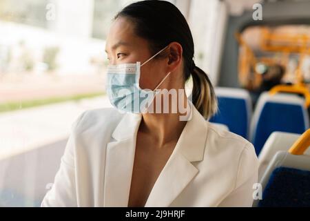 Donna d'affari che indossa maschera protettiva viso che passa in tram Foto Stock