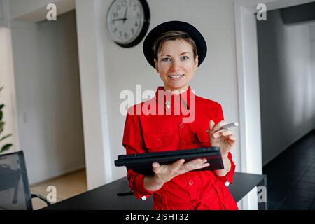 Donna d'affari sorridente con un tablet PC in ufficio Foto Stock