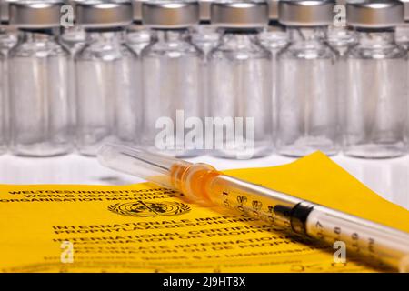 Certificato di vaccinazione internazionale con diverse fiale e siringa per ferite Foto Stock