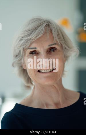 Donna anziana felice con capelli grigi Foto Stock