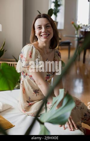 Donna matura felice vestito seduta sul divano a casa Foto Stock