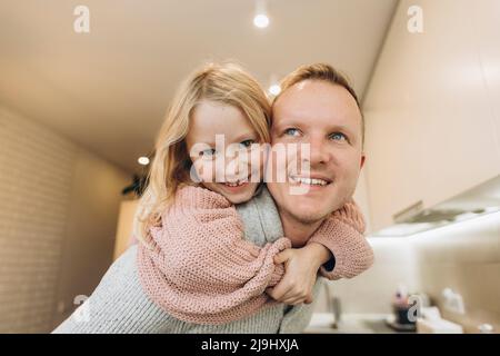 Padre che dà il giro di piggyback alla figlia a casa Foto Stock