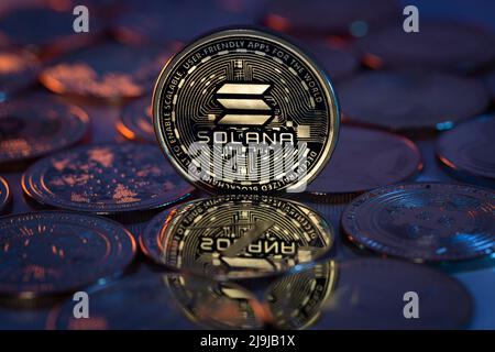 Solana Sol Cryptocurrency Coin fisico posto su cripto altcoins e illuminato con luci arancioni e blu nel Backgrone scuro. Scatto macro. Selettivo foc Foto Stock