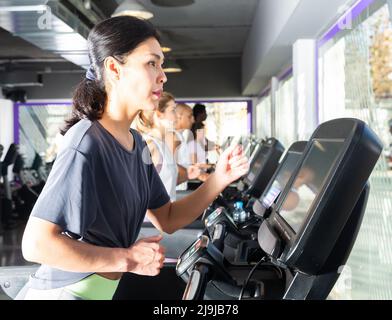 Donna sportiva che corre sul tapis roulant in palestra Foto Stock