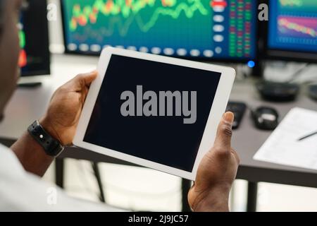 Primo piano di un uomo irriconoscibile che lavora su un tablet digitale in un moderno ufficio di intermediazione, schermo nero vuoto, spazio di copia Foto Stock