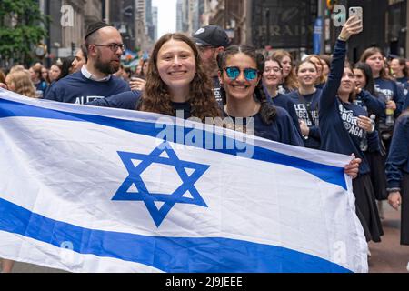 New York, US, 22/05/2022, i partecipanti che detengono la bandiera israeliana marciano lungo la Fifth Avenue durante la Felebrate Israel Parade a New York City. Il JCRC-NY celebra la Parata d'Israele è la più grande espressione di solidarietà con lo Stato ebraico al mondo. Unisciti a noi e fai il tifo per più di 40.000 marchers, decine di favolosi carri allegorici, gruppi di marching e alcuni eccitanti artisti ebrei e israeliani! La sfilata procede fino alla Fifth Avenue da 57th Street a 74th Street, mostrando passione per lo Stato di Israele e amore per la comunità ebraica globale. Foto Stock