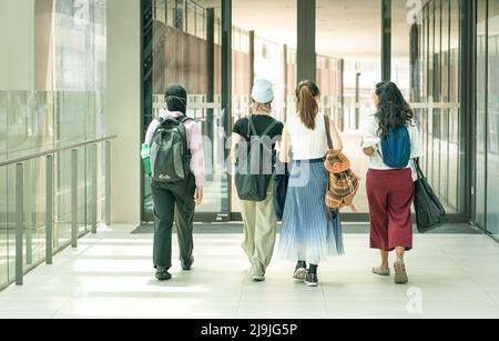 Gruppo di amici studenti universitari che camminano insieme nella hall. Vista posteriore. Foto Stock